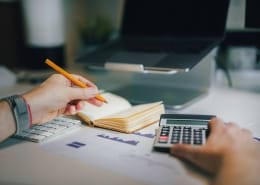a person sitting at a desk with a calculator and a notebook