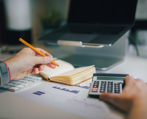 a person sitting at a desk with a calculator and a notebook