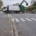 Un camion de collecte des déchets manœuvre à un croisement, avec des sacs de déchets en désordre sur le bord de la route dans un quartier résidentiel