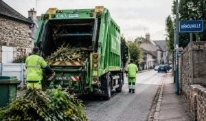 Photo réaliste d'un camion de collecte des déchets verts en action, chargé de branches et feuillage, sur une rue de Bénouville
