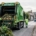 Photo réaliste d'un camion de collecte des déchets verts en action, chargé de branches et feuillage, sur une rue de Bénouville