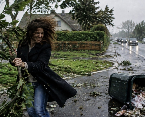 Photo réaliste montrant une femme luttant contre des vents violents, tenant une branche d'arbre